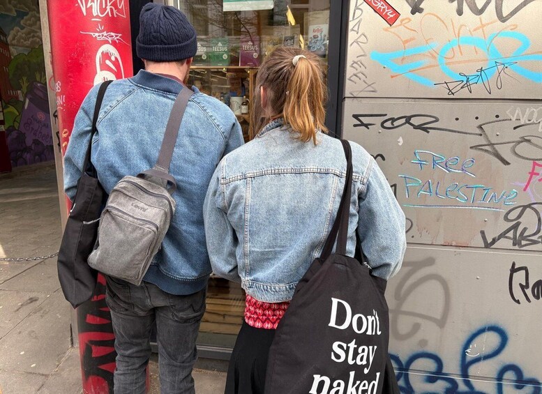 Two people walking past a store with graffiti on the wall. 3