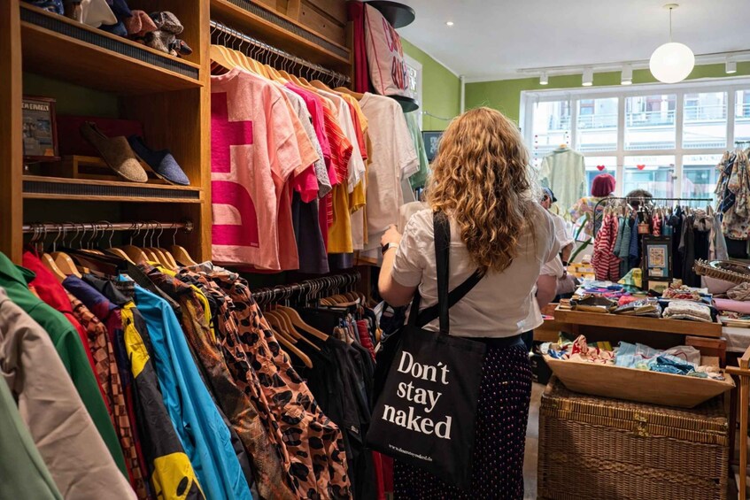 A person browsing through a clothing store with various garments on display. 4