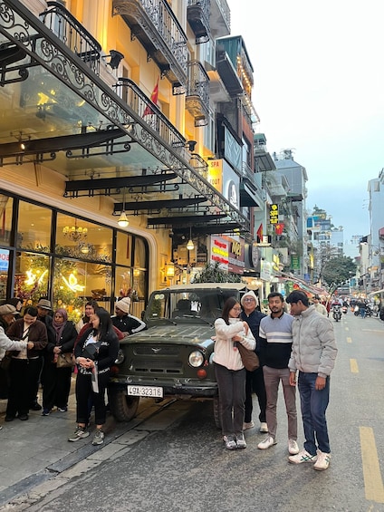 A street with a parked vehicle, pedestrians, and buildings with signs. 4