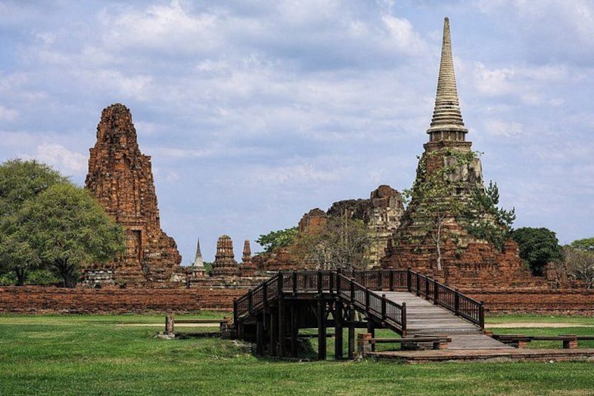 A temple complex with a prominent stupa and a wooden bridge. 4