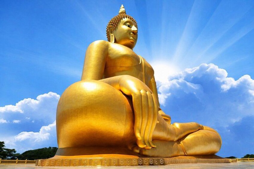 A large golden Buddha statue seated in a meditative pose against a clear blue sky with clouds. 5