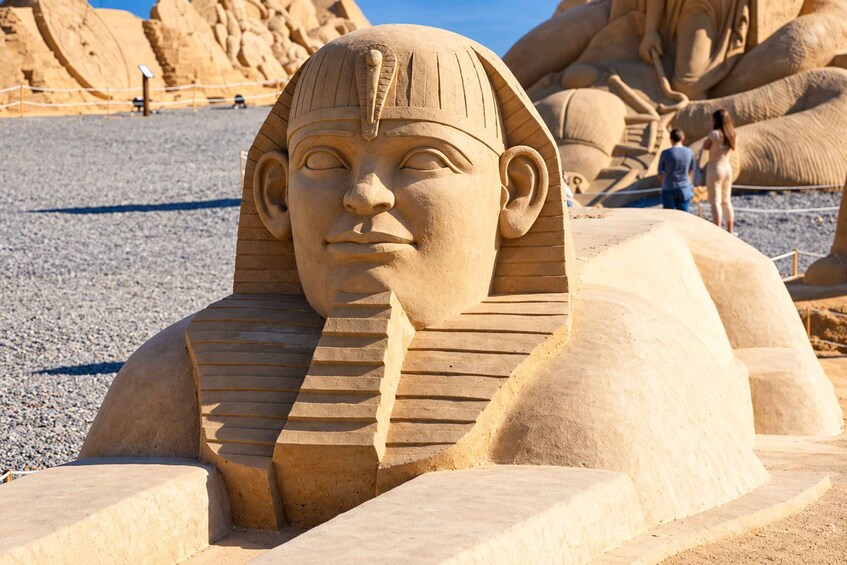 En stor sandskulptur af et faraos ansigt med en pyramide i baggrunden. 3