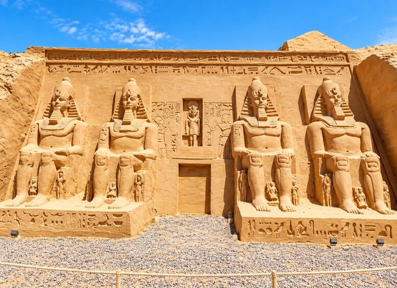 En stor sandstensbygning med tre siddende figurer, hver med en særpræget hovedbeklædning, og hieroglyf-inskriptioner. 2