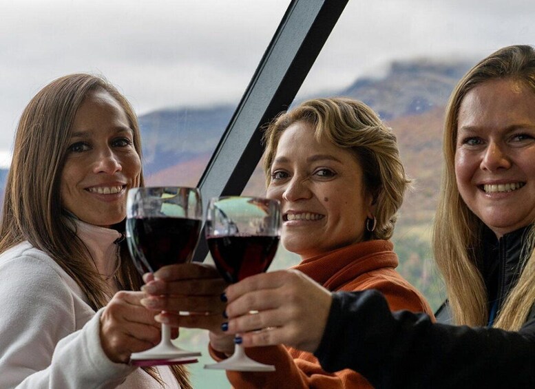 Three people toasting with wine glasses, with a mountainous landscape in the background. 1