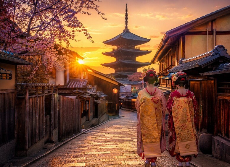 A traditional Japanese street at sunset with cherry blossoms, a pagoda, and two women in kimonos. 2