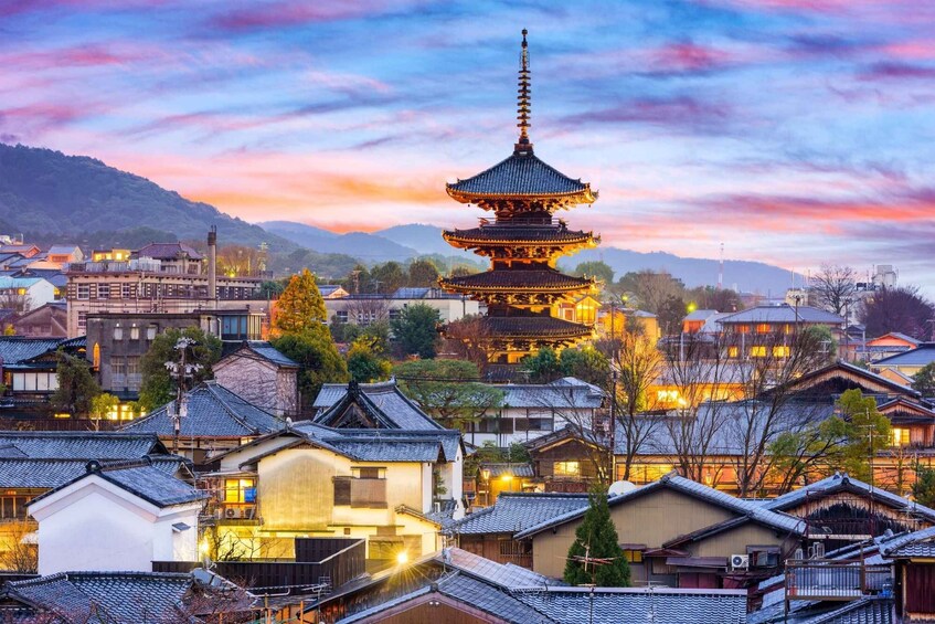 A traditional Japanese pagoda with multiple tiers, surrounded by residential buildings and a mountainous backdrop during twilight. 2
