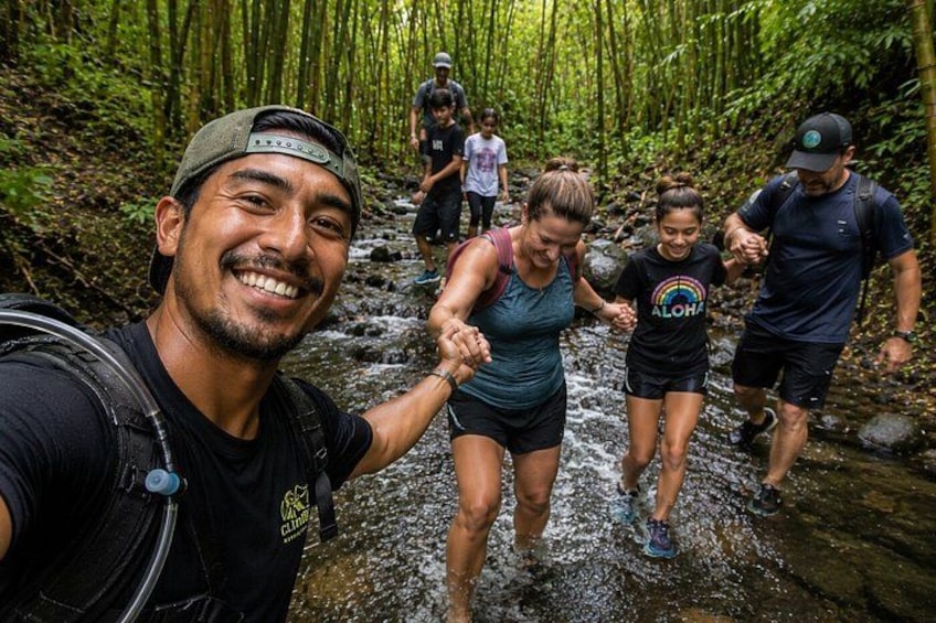 A group of people hiking through a forested area with a stream. 2