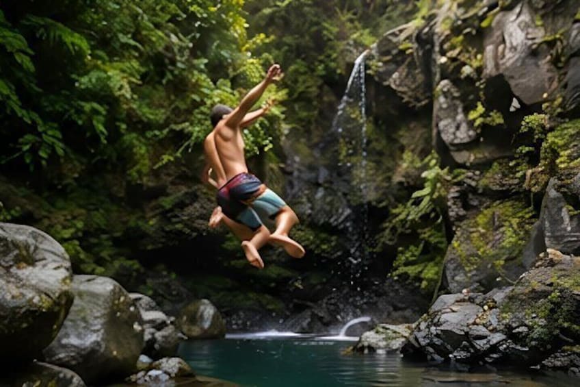 A person jumping into a natural pool surrounded by rocks and greenery. 3