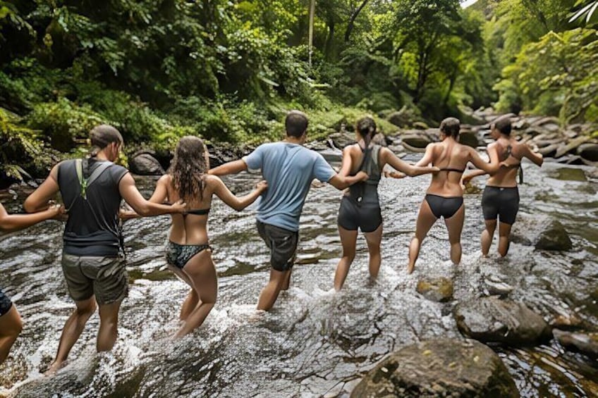 A group of people crossing a rocky stream in a forested area. 4