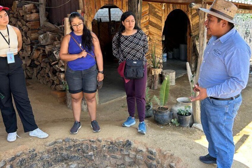 A group of people standing near a rustic building with a fire pit in the foreground. 2