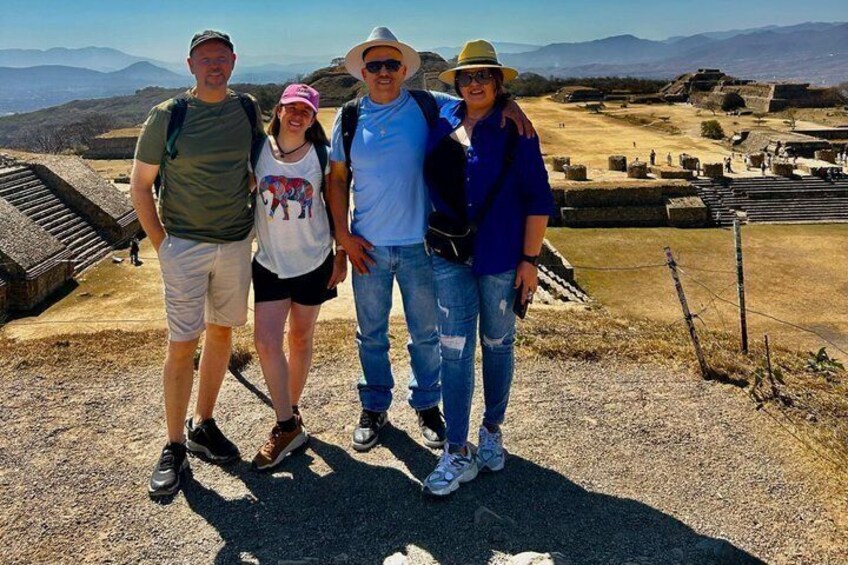 A group of people standing on a rocky outcrop with a historical site in the background. 1