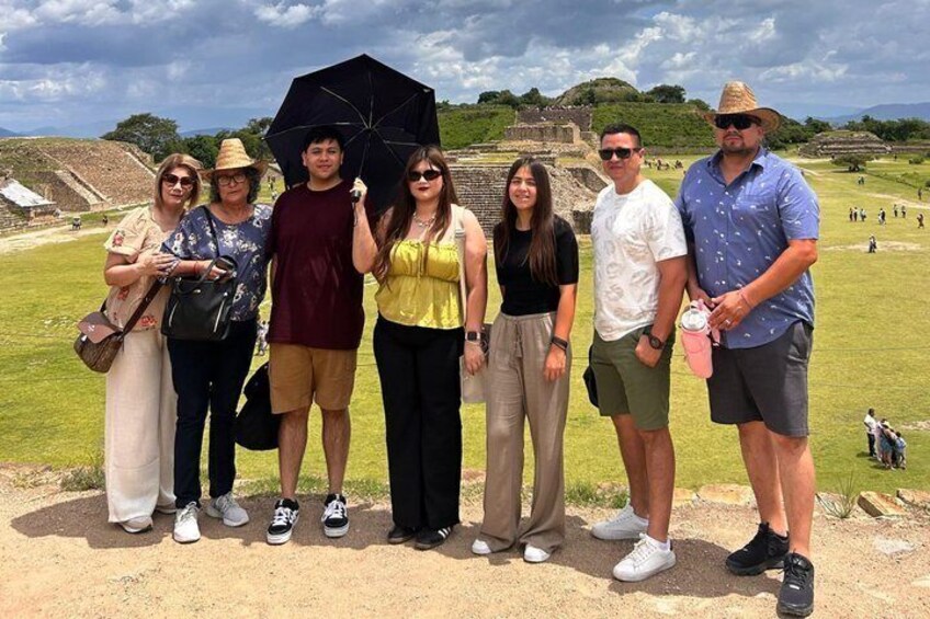 A group of people standing on a grassy field with ancient ruins in the background. 3