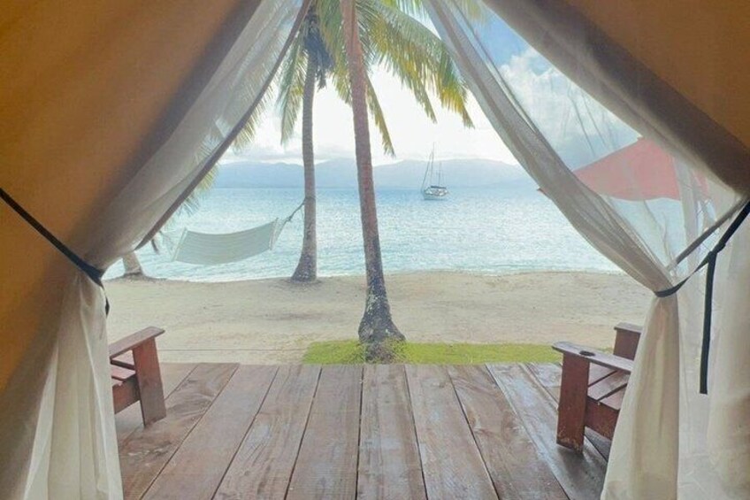 A beach view from a tent with a hammock and wooden deck. 5