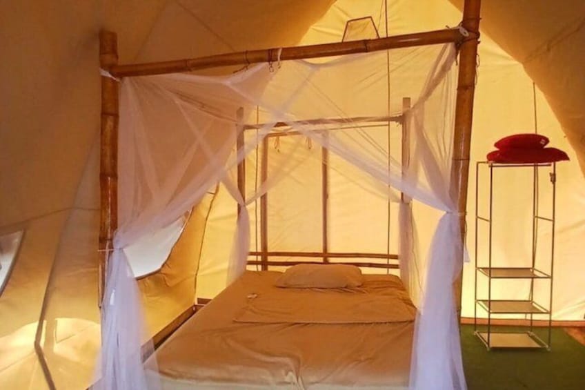 A tent with a bed, mosquito net, and a metal shelf. 2