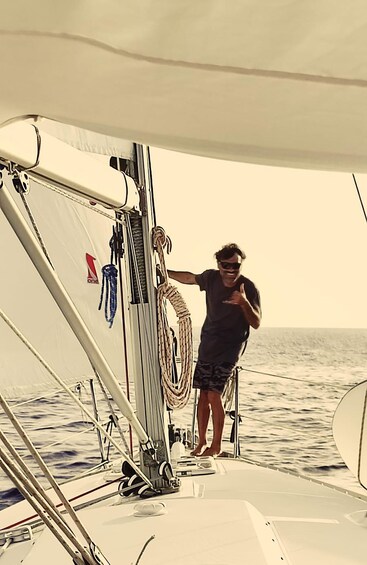 A person standing on a sailboat's deck with ropes and a sail visible. 4