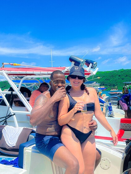 A couple on a boat with a clear blue sky and green hills in the background. 1