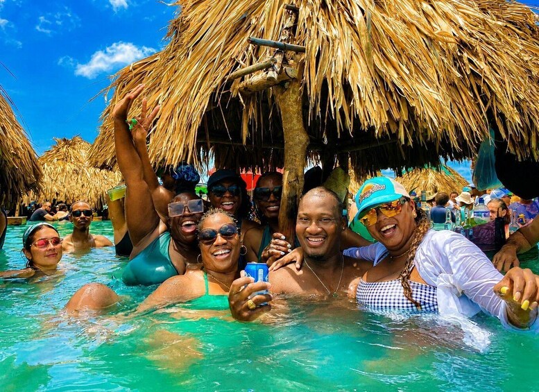 People in a pool with thatched-roof huts in the background. 5