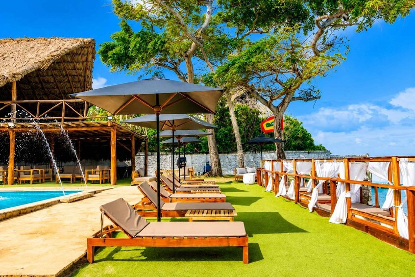 A poolside area with lounge chairs, umbrellas, and a thatched-roof structure. 5