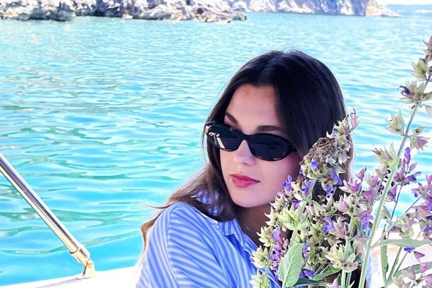 A person on a boat near turquoise water with rocky cliffs in the background. 4
