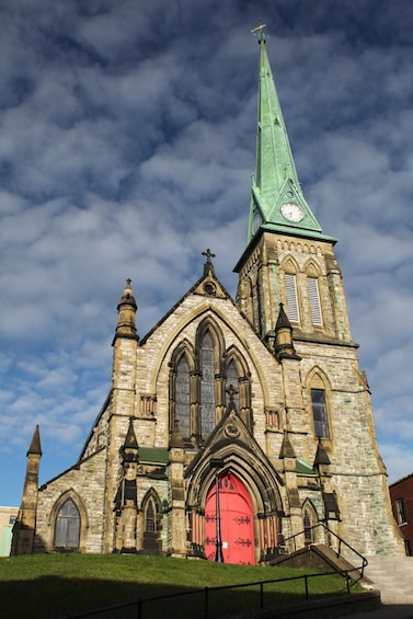 A historic church with a prominent green spire and a red door. 2