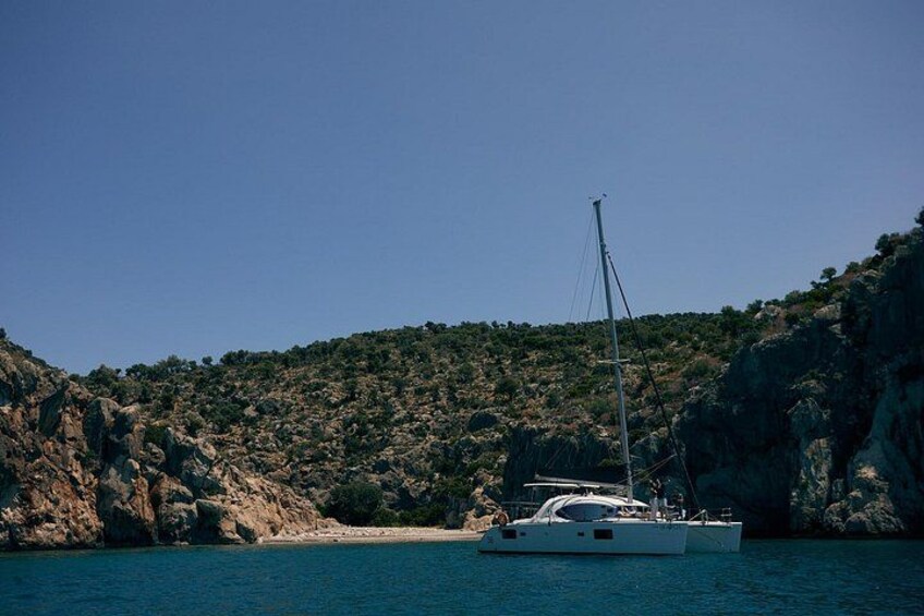 Un velero anclado cerca de una costa rocosa con cielo despejado. 4