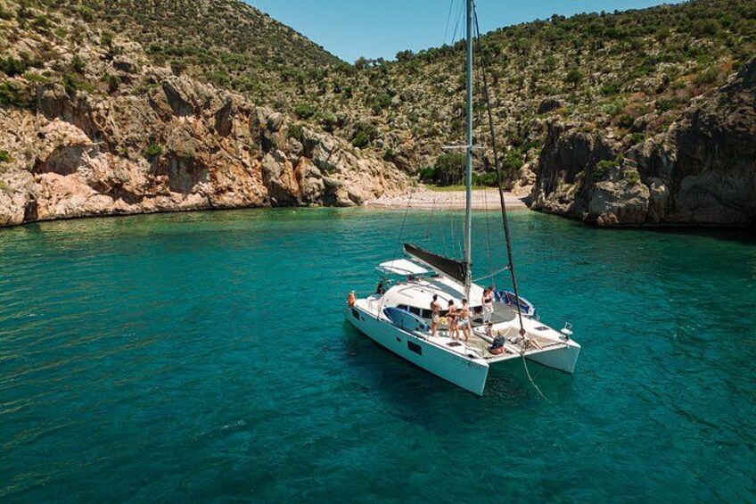 Un velero en aguas turquesas con colinas rocosas al fondo. 3
