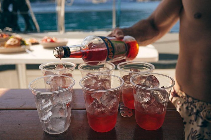 Una persona sirve un líquido rojo en vasos de plástico con hielo sobre una mesa de madera. 3