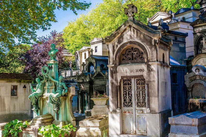 A cemetery with ornate tombstones and a statue of a seated figure. 4