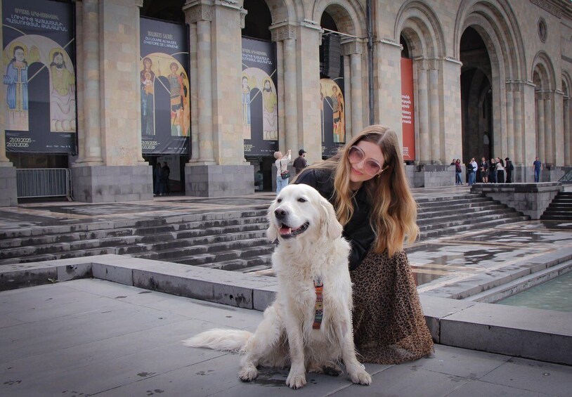A person with a dog in front of a building with large columns and banners. 2