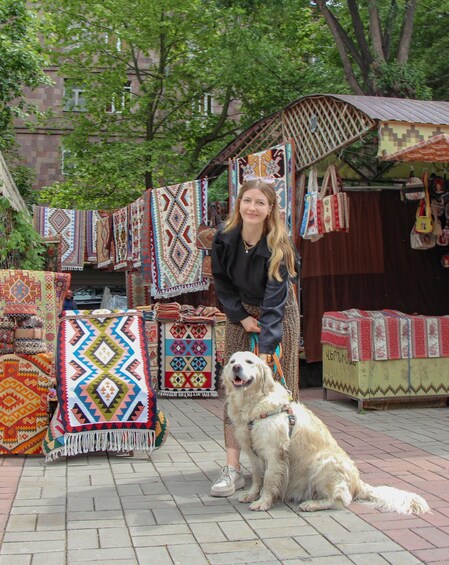A person with a dog in front of a market stall with colorful textiles. 4