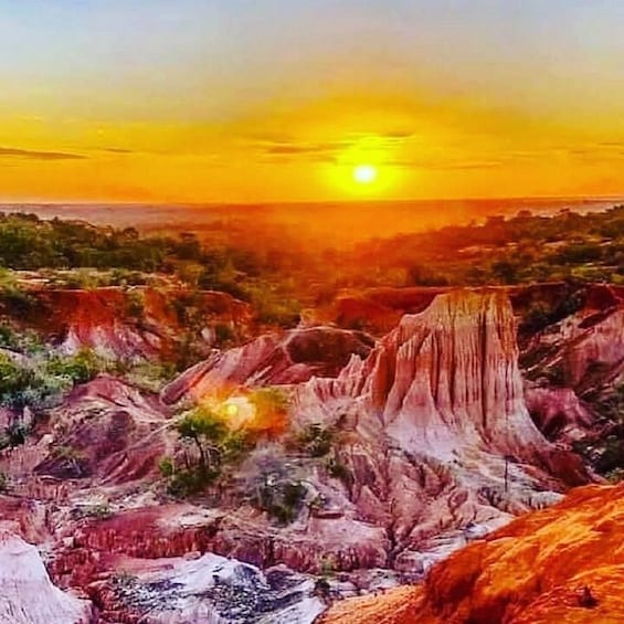 A sunset over a rugged landscape with distinct red and white rock formations. 5