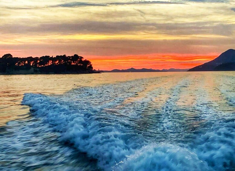 A body of water with waves, a sunset, and a distant mountain range. 3