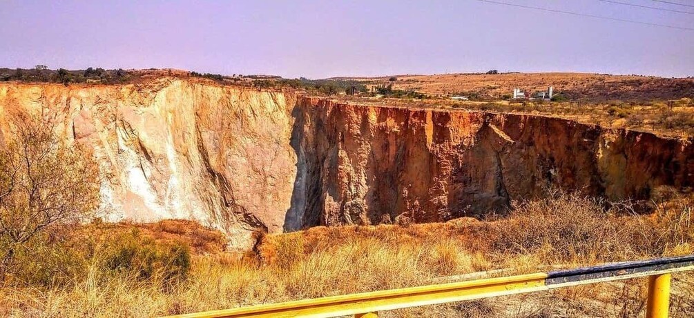 A deep canyon with a yellow guardrail in the foreground. 5