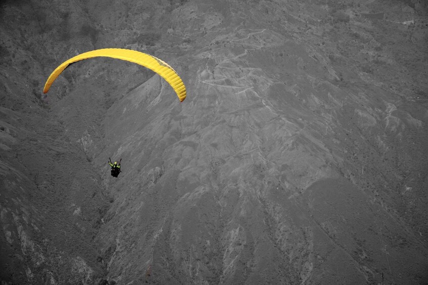 A person paragliding over a barren, rocky landscape. 2