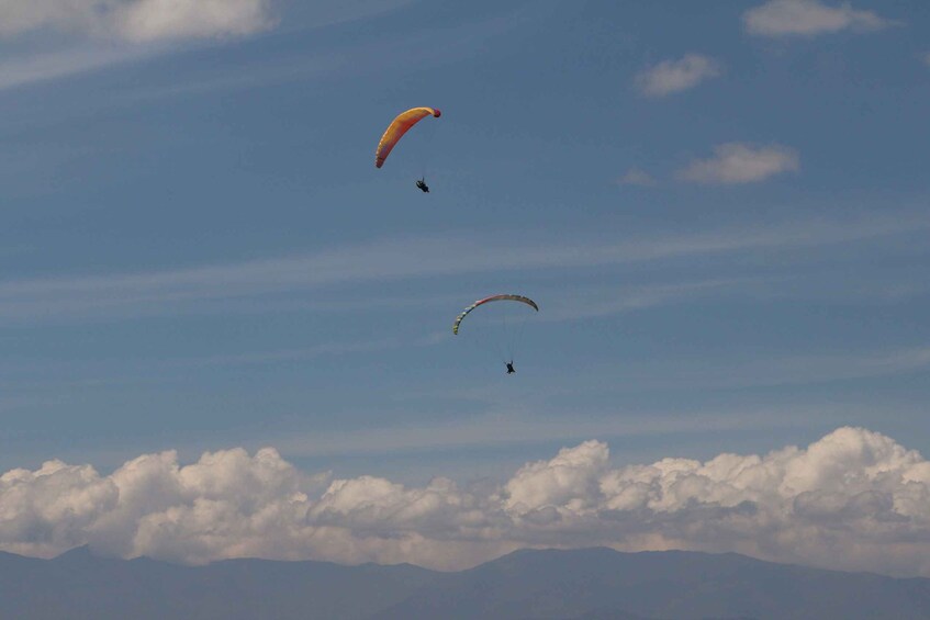 Two paragliders and a mountain range in the background. 3