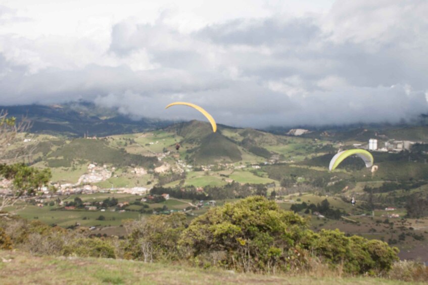 A landscape with two paragliders and a small town in the valley. 5