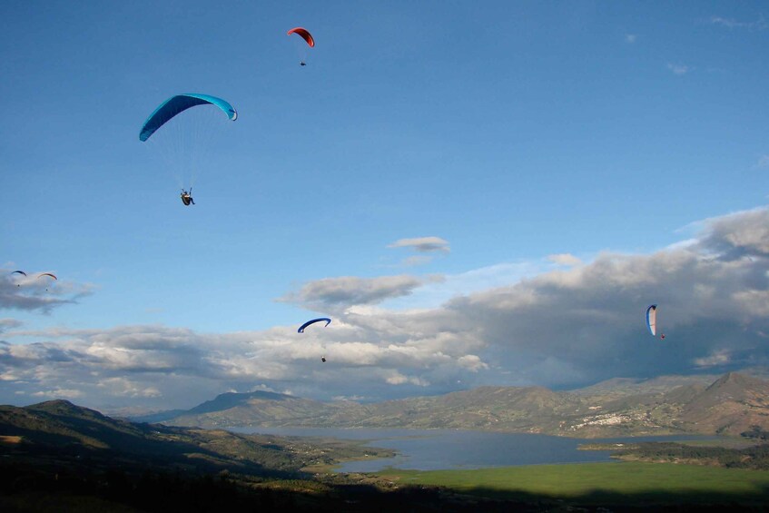 Paragliders flying over a lake with mountains in the background. 1