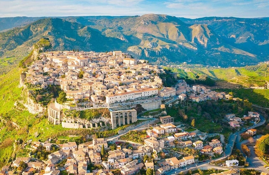 A mountainous town with historic architecture, terraced fields, and a prominent church. 1