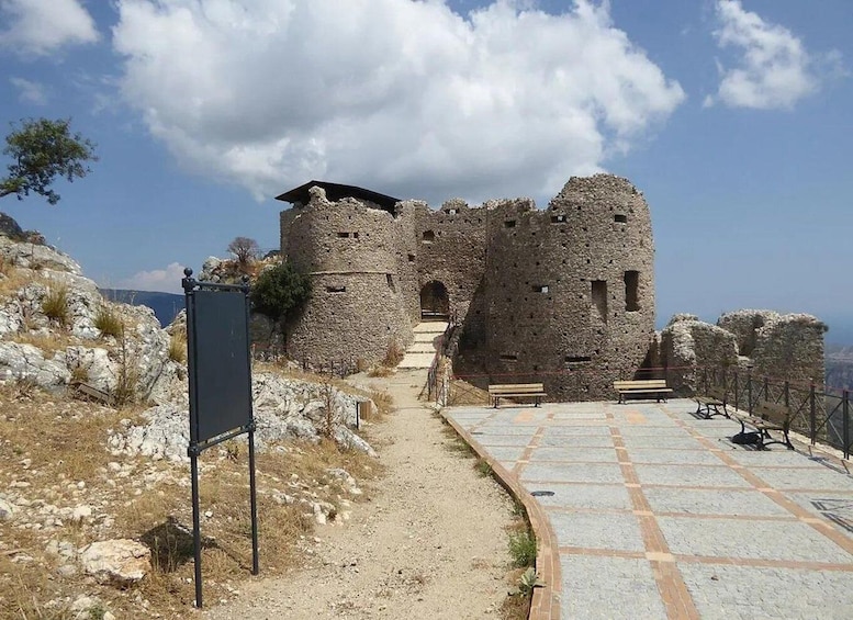 A stone castle ruin with a paved pathway leading to its entrance. 2
