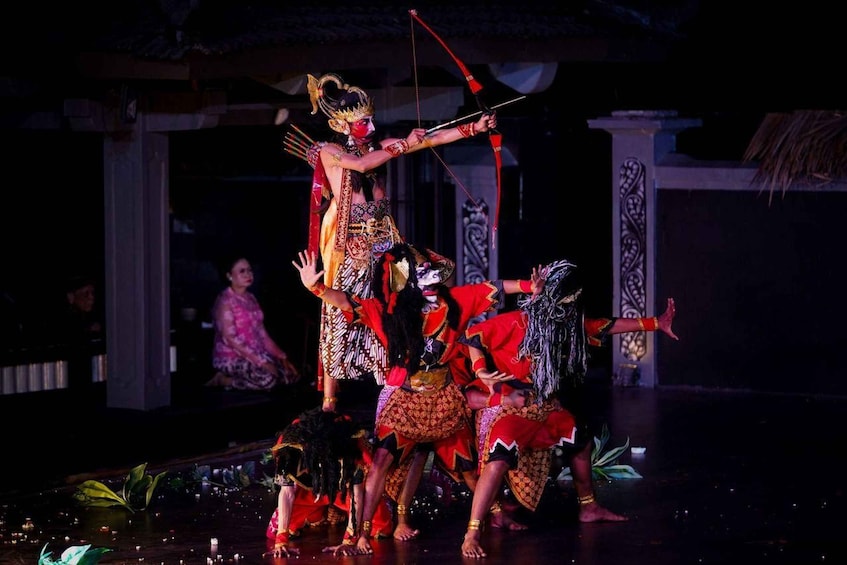 A theatrical performance with actors in traditional costumes, a stage with a backdrop of columns, and a darkened audience area. 4