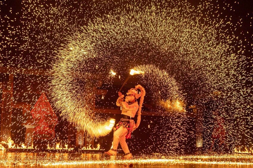 A performer with a fire prop in a dark setting, surrounded by sparks. 1