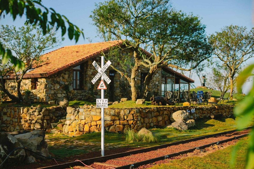 A stone building with a red roof, a railroad crossing sign, and a stop on red signal sign. 4