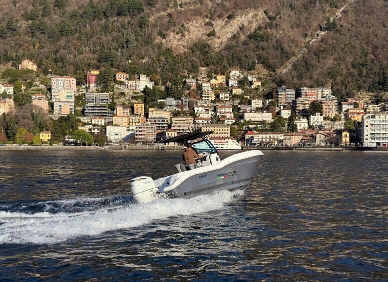 A white speedboat with a person on board, moving through a body of water with a backdrop of a densely built hillside town. 3