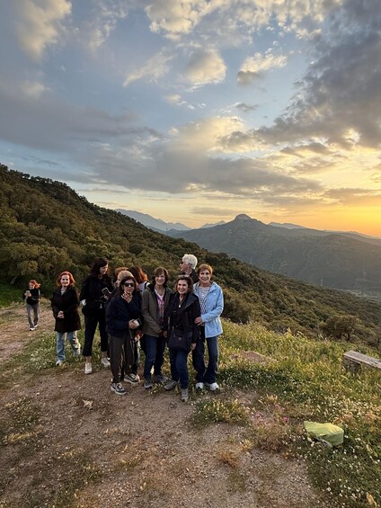 A group of people on a mountain trail with a sunset in the background. 2