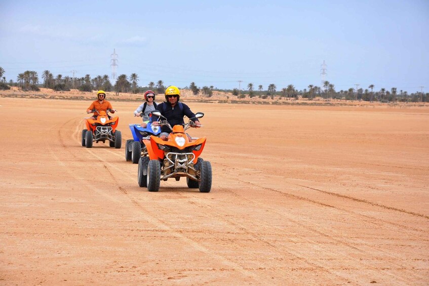 Three off-road vehicles on a dirt road with palm trees and power lines in the background. 4