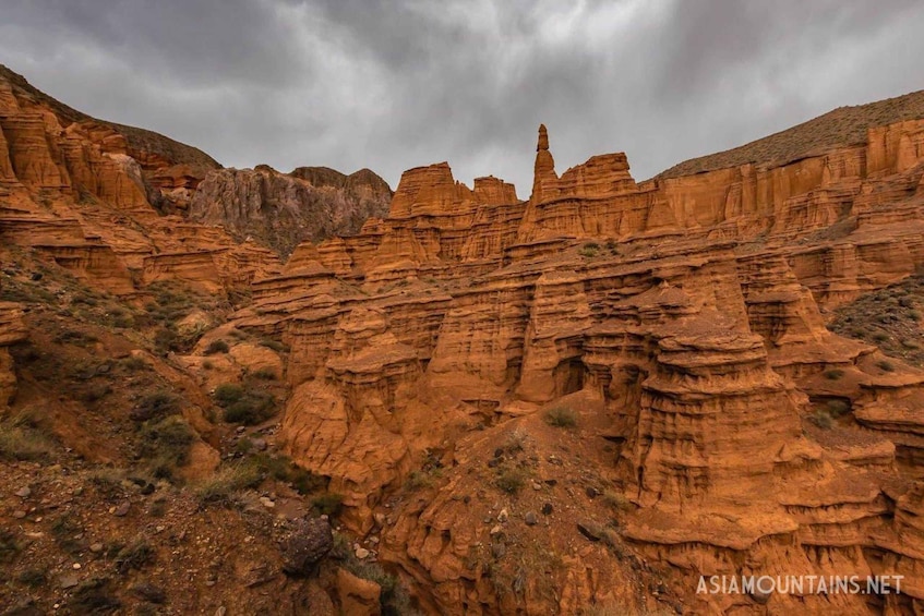 A rugged canyon landscape with layered rock formations and sparse vegetation. 5