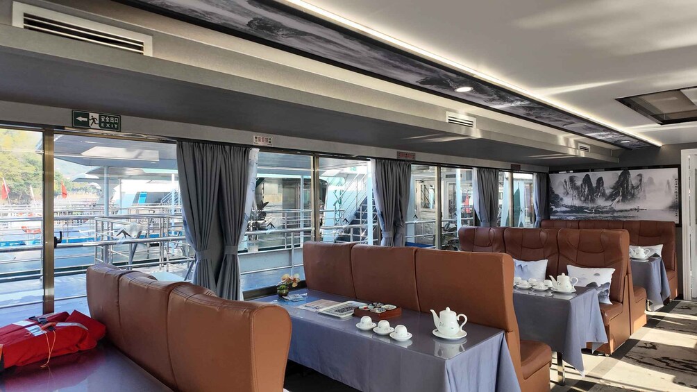 A modern dining area with leather seating, tables set for tea service, and a view of the dock. 4