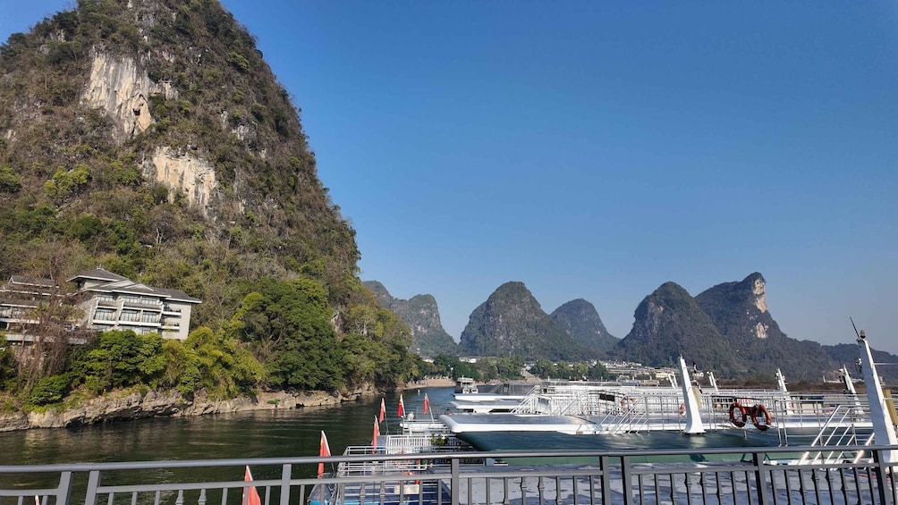A river with a boat docked, a building, and a mountainous landscape. 2