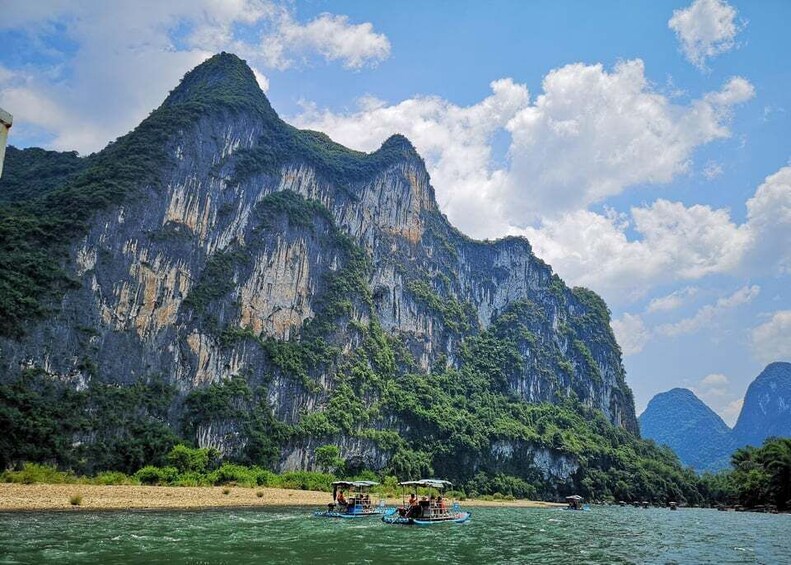 A river with boats and a large limestone cliff. 3