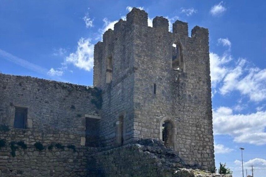 A stone castle with a tall tower, arched windows, and a clear blue sky. 3